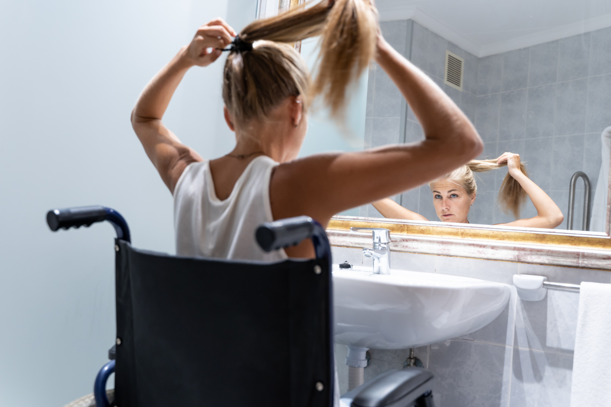 Wheelchair-accessible shower room in Portsmouth with young woman using adaptive wash basin designed for easy wheelchair access.